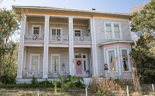 A historic two-story stone home under live oaks in Burnet, TX, the Highland Lakes county seat in 78611
