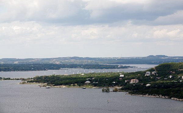 Lake Travis at full capacity off Lakeway, TX, with waterfront homes tucked into the wooded shoreline of 78734