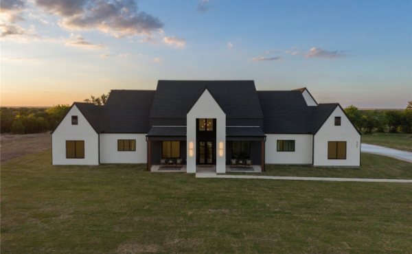 A modern Hill Country farmhouse at dusk on an open Leander, TX lot, representative of new construction in the 78641 market
