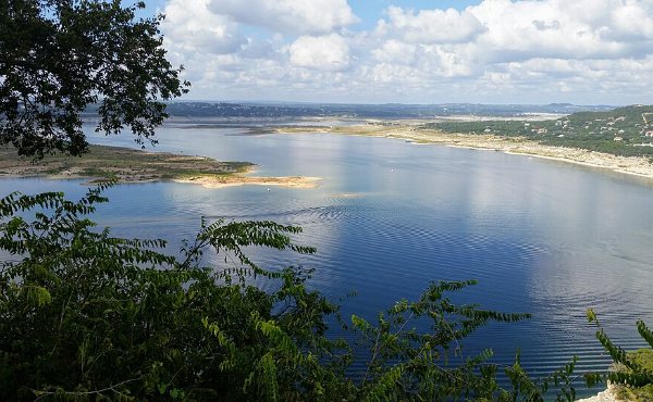 Deep blue Lake Travis water meeting pale limestone shoreline and cedar hills near Point Venture, TX in 78645